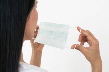 Bir kadın, Coronavirus 'un (COVID-19) yayılmasına karşı koruyucu bir maske takar. Cerrahi maske. Tıbbi maske. Yüz maskesi.