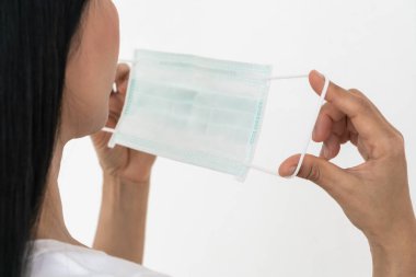 Bir kadın, Coronavirus 'un (COVID-19) yayılmasına karşı koruyucu bir maske takar. Cerrahi maske. Tıbbi maske. Yüz maskesi.