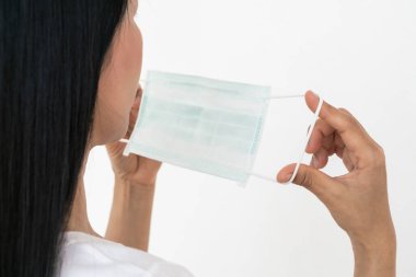 Bir kadın, Coronavirus 'un (COVID-19) yayılmasına karşı koruyucu bir maske takar. Cerrahi maske. Tıbbi maske. Yüz maskesi.