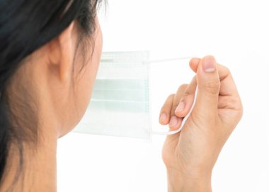 Bir kadın, Coronavirus 'un (COVID-19) yayılmasına karşı koruyucu bir maske takar. Cerrahi maske. Tıbbi maske. Yüz maskesi.