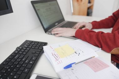 açık defter ile masaya oturan dizüstü kullanan adam