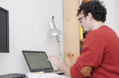 ofiste masada oturan dizüstü kullanan adam