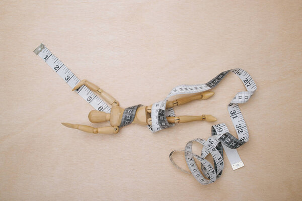 деревянный манекен, завернутый в рулетку
