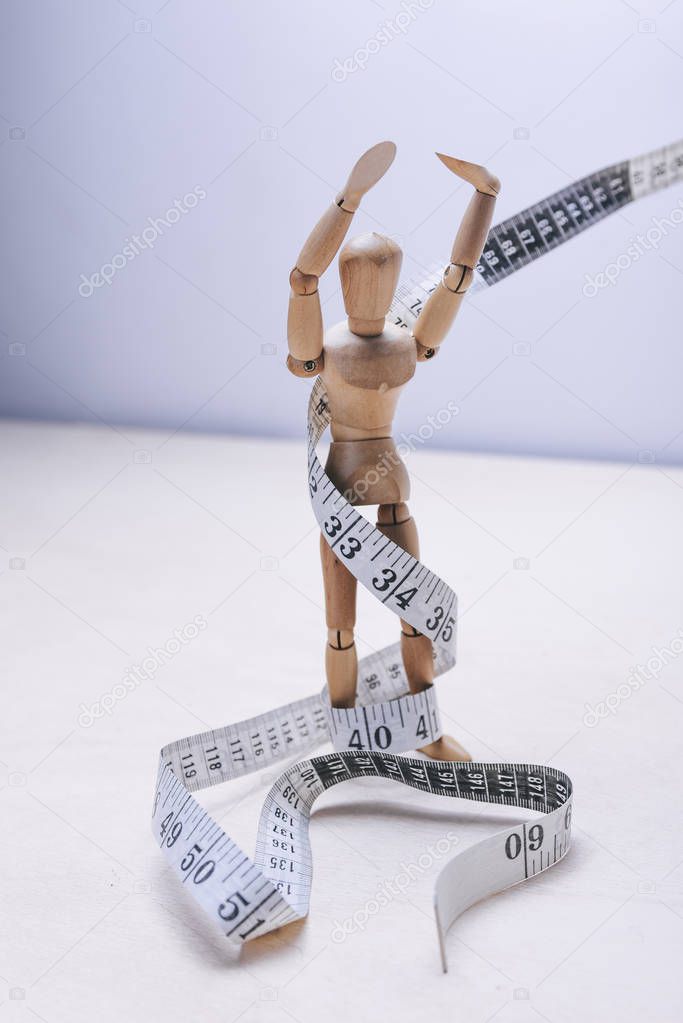 wooden mannequins with tape measure on light background