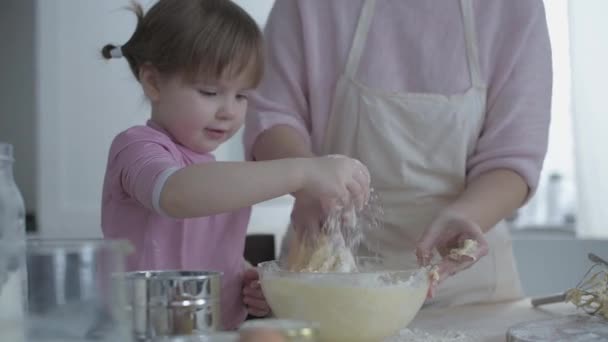 妈妈带着一个孩子在厨房准备糕点 家庭烹饪 年轻的母亲教女儿做饭 产品在桌子上 真正的家庭生活 家庭之夜 妈妈和女儿一起 — 图库视频影像
