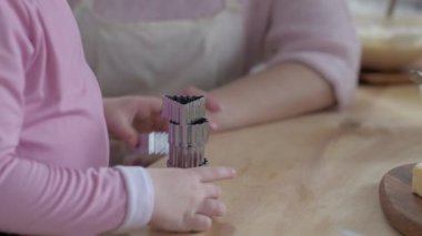 Mutfakta annesiyle yemek hazırlayan küçük bir kız. Unu at. Anne ve kızı mutfakta aşçılık oynuyorlar. Kız tatlı pişirirken yaramazdır. Birlikte oynayın.