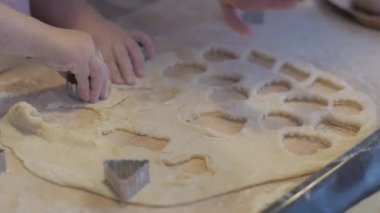 Küçük kız annesine mutfakta pişirmede yardım ediyor. Kurabiyeleri kurabiye keskisiyle kes. Hamuru pişirme tepsisine koyuyorum. Kurabiyeleri kağıdın üzerine boşalt..