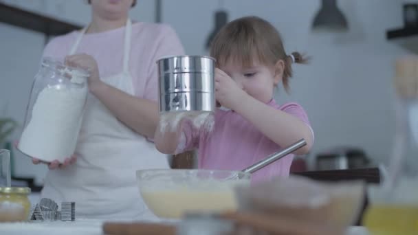 台所の娘とお母さんは皿の上の生地をこねる 台所では女の子がいたずら 母は料理人の娘と遊ぶ 母親は子供に料理を教える 陽気調理ベーキング — ストック動画