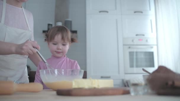 台所の娘とお母さんは皿の上の生地をこねる その少女は台所でいたずらをする 母は料理人の娘と遊ぶ 母親は子供に料理を教える 陽気調理ベーキング — ストック動画