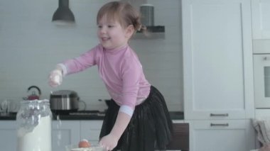 Annesi ve kızı mutfakta hamuru tabakta yoğuruyor. Kız mutfakta yaramazlık yapıyor. Annesi aşçı olan küçük kızıyla oynuyor. Anne çocuğuna yemek yapmayı öğretir. Neşeli yemek pişirme.