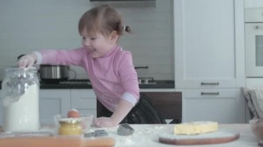Annesi ve kızı mutfakta hamuru tabakta yoğuruyor. Kız mutfakta yaramazlık yapıyor. Annesi aşçı olan küçük kızıyla oynuyor. Anne çocuğuna yemek yapmayı öğretir. Neşeli yemek pişirme.