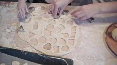 Küçük kız annesine mutfakta pişirmede yardım ediyor. Kurabiyeleri kurabiye keskisiyle kes. Hamuru pişirme tepsisine koyuyorum. Kurabiyeleri kağıdın üzerine boşalt..