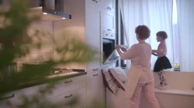 Kız tavayı fırına koydu. Kurabiye tepsisi. Anne kızına yemek yapmayı öğretiyor..