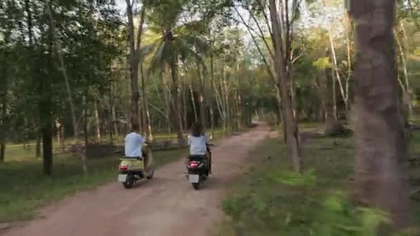 两个骑摩托车的 一个男的和一个女的骑自行车穿过丛林 椰子种植园上的乡村小路 惊人的冒险仙岛 — 图库视频影像