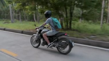 Kasklı genç bir motosikletçi ormanda güçlü bir motosiklet sürüyor. Motosiklet hız kazanıyor. Motosikletli solladı.