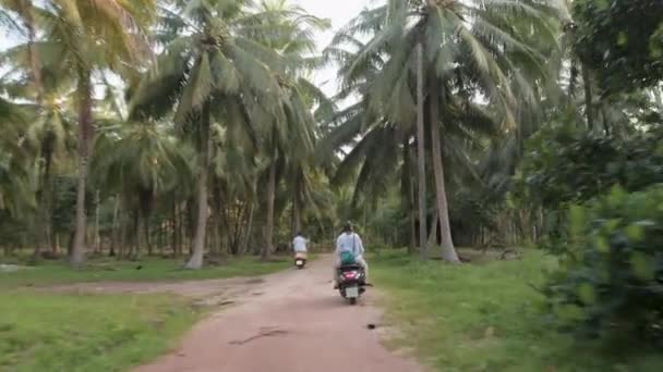 两个骑摩托车的 一个男的和一个女的骑自行车穿过丛林 椰子种植园上的乡村小路 惊人的冒险仙岛 — 图库视频影像