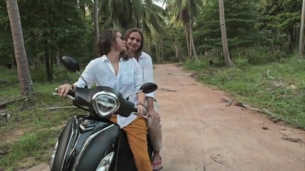在热带地区的路上 年轻漂亮的姑娘们骑自行车 自由快乐的女孩都在微笑 戴眼镜的女孩都在笑 两个去椰子种植园 — 图库视频影像