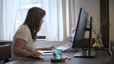 Genç bir İspanyol kadın tecritte video iletişimi öğretiyor. Serbest çalışan güzel bir kız evde çalışıyor. İş kadınları laptopun önünde iş başında. Ev mobilyaları. Sıcak ev ışığı.