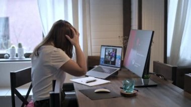 Genç ve güzel bir kadın dizüstü bilgisayarda çalışıyor. Gülümseyen kız öğretmen online dersler veriyor. İş videosu konferansı. Ofis evde. Kişisel izolasyon koşullarında çalış.