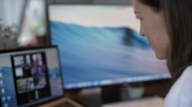 Genç ve güzel bir kadın dizüstü bilgisayarda çalışıyor. Gülümseyen kız öğretmen online dersler veriyor. İş videosu konferansı. Ofis evde. Kişisel izolasyon koşullarında çalış.
