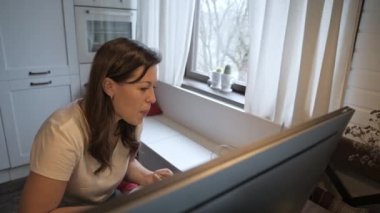 Genç, güzel bir kadın bilgisayar ekranına bakıyor. Uzaktan kumanda. Çevrimiçi öğretmenlik. Öğretmen egzersizi gösterir. Nöropsikolog uzaktan kumandayla çalışıyor. Ev eşyaları..