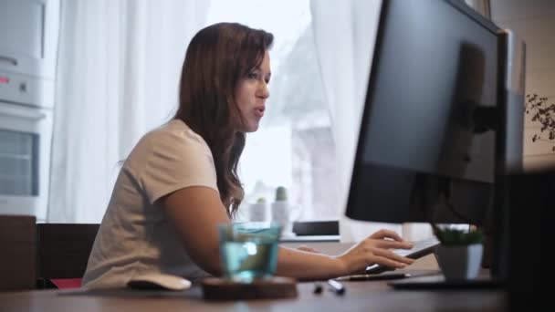 一位年轻的西班牙妇女孤立地教视频交流 一个漂亮的自由撰稿人在家里工作 在笔记本电脑前工作的女商人 家居装饰 舒适的家灯火 桌上杯子里的水 — 图库视频影像