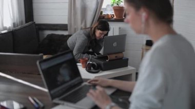 İki güzel çok ırklı kız evde çalışıyor. Bağımsızlar birlikte çalışır. Genç güzel kadınlar dizüstü bilgisayarların önünde oturuyorlar. Laptop ekranına bakıyor. İnternette sörf yapmak. Canlı iletişim.