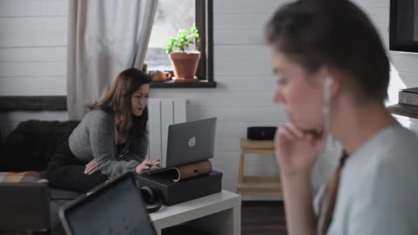 两个漂亮的多族裔女孩在家里工作 自由职业者一起工作 年轻漂亮的女人正坐在笔记本电脑前 它看着手提电脑的屏幕 在网上冲浪 现场通信 — 图库视频影像