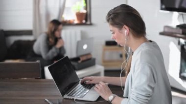 İki güzel çok ırklı kız evde çalışıyor. Bağımsızlar birlikte çalışır. Genç güzel kadınlar dizüstü bilgisayarların önünde oturuyorlar. Laptop ekranına bakıyor. İnternette sörf yapmak. Canlı iletişim.