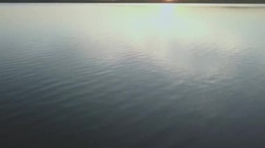 Suyun üzerinde uçmak. Gölde gün batımı. Gökteki bulutların yansıması bir göletin sakin sularında. Göldeki güneşin yansıması..