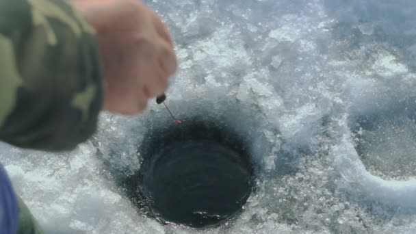 Человек ловит рыбу на зимнем озере — стоковое видео