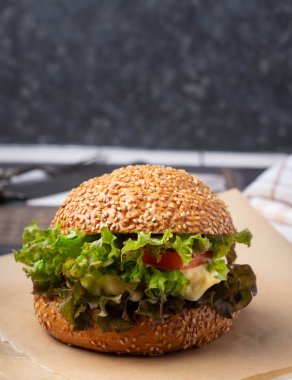 Lezzetli ızgara sığır burger, marul ve peynirli. Kahverengi kağıt parçalarıyla servis ediliyor.