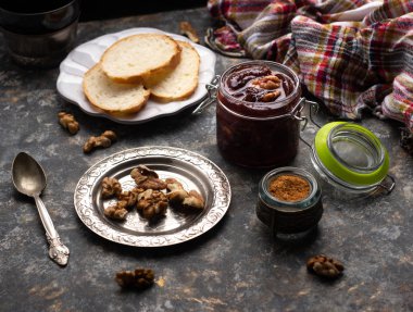 Mutfak masasının üzerinde ceviz ve Fransız ekmeği ile ev yapımı erik reçeli reçeli kavanozu. Sağlıklı tatlı tarifleri konsepti. 