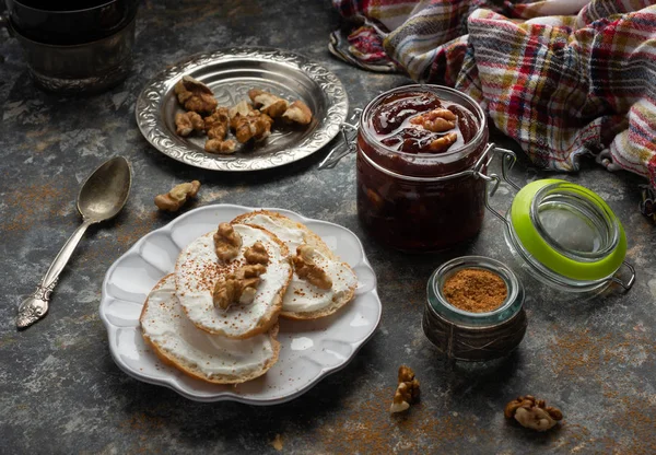 Mutfak masasının üzerinde ceviz ve Fransız ekmeği ile ev yapımı erik reçeli reçeli kavanozu. Sağlıklı tatlı tarifleri konsepti