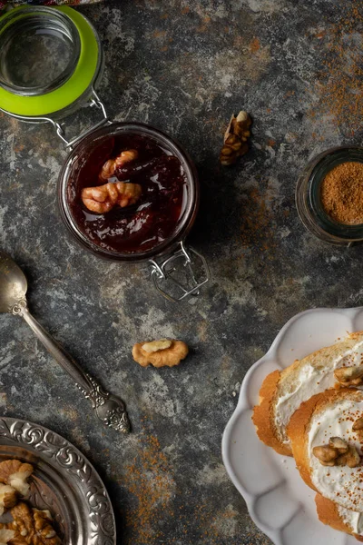 Mutfak masasında ceviz ve kaşıkla ev yapımı erik reçeli reçeli kavanozu. Sağlıklı tatlı tarifleri konsepti. Üst görünüm.