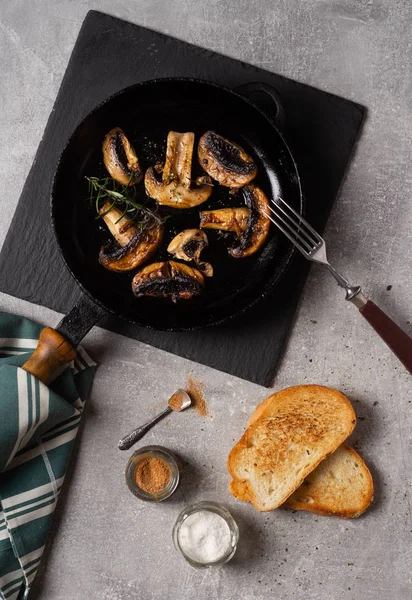 Kızartma tavasında leziz kızarmış mantarlar, ekmek, çatal masada, üst manzara.