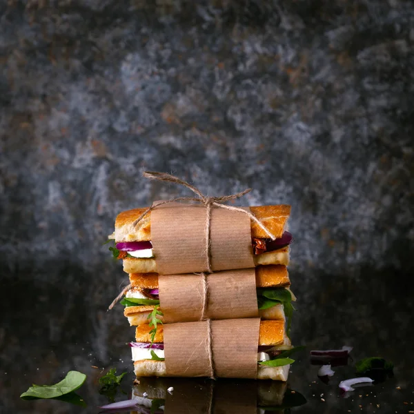 Yemek, kahvaltı, sabah ve öğle yemeği konsepti. Peynirli, marullu ve kurutulmuş domatesli taze ekmek sandviçi