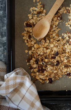 Pişirme tepsisinde ev yapımı tahıl gevreği, ahşap kaşık, tutkal, kahvaltı. Üst görünüm.