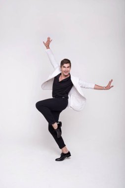 Beyaz elbiseli beyaz arka plan üzerinde gülümseyen yakışıklı bir adam. Dans hareket. Şık adam.
