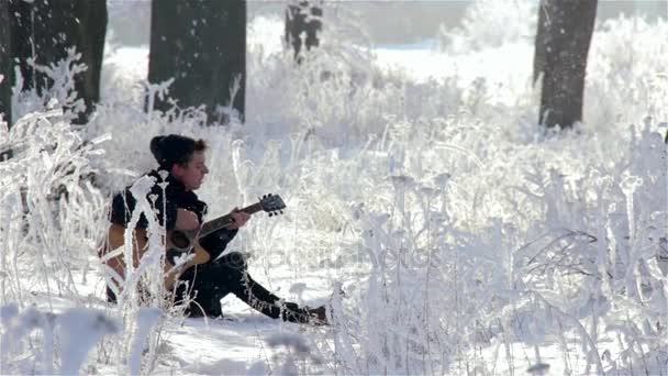 Ung man spelar gitarr och sjunger i parken — Stockvideo