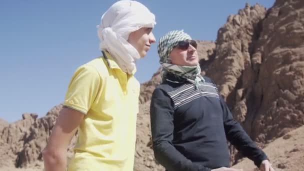 Отец и сын разговаривают возле пустынных гор — стоковое видео
