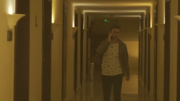 Молодой человек разговаривает по телефону в отеле — стоковое видео