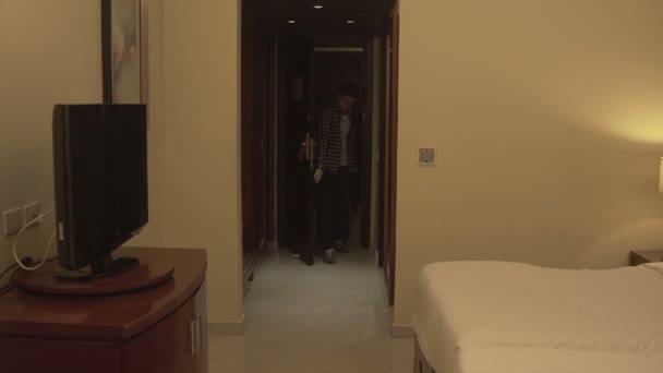 Joven con equipaje Check in habitación de hotel — Vídeo de stock