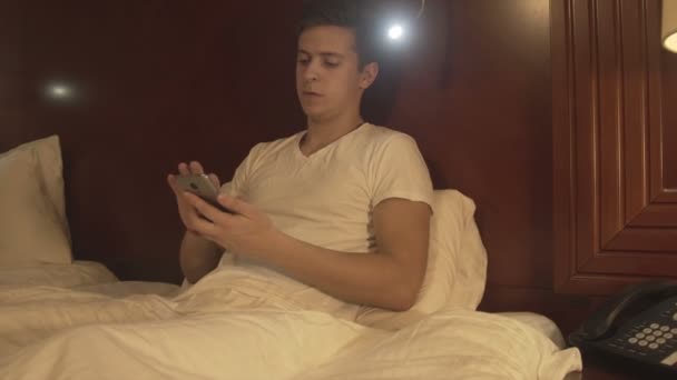 Relaxed young man holding the phone typing message — Stock Video