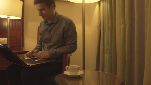 Man smiles using laptop in home interior. — Stock Video