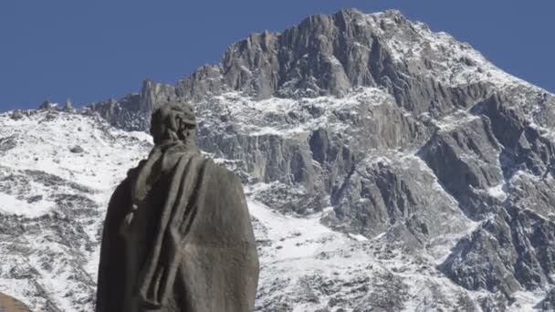 Escultura de anónimo frente a la cima cubierta de nieve de la montaña — Vídeos de Stock