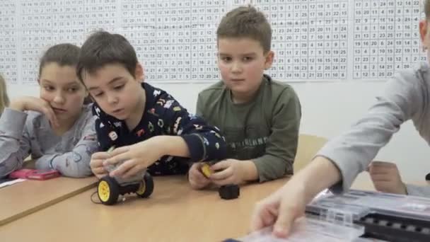 Van schattige kinderen bouwen gemotoriseerde robot op basisschool — Stockvideo