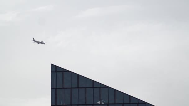 Avião perto da fachada moderna do edifício enquanto voa pelo céu . — Vídeo de Stock
