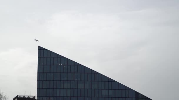 Repülőgép közelében modern épület homlokzat, miközben repül az égen. — Stock videók