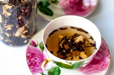 Bir fincan çay. Fincanda büyük çay yaprakları. Bir kutu çay. Meyveli büyük yaprak çayı.